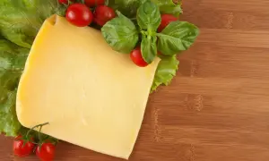 Pyszny ser żółty dla psa, z pomidorkami i bazylią na desce.