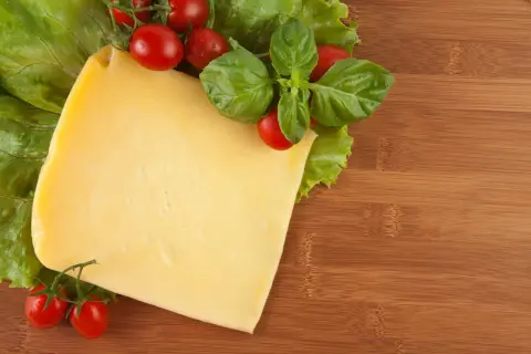 Pyszny ser żółty dla psa, z pomidorkami i bazylią na desce.