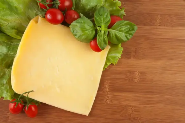 Pyszny ser żółty dla psa, z pomidorkami i bazylią na desce.